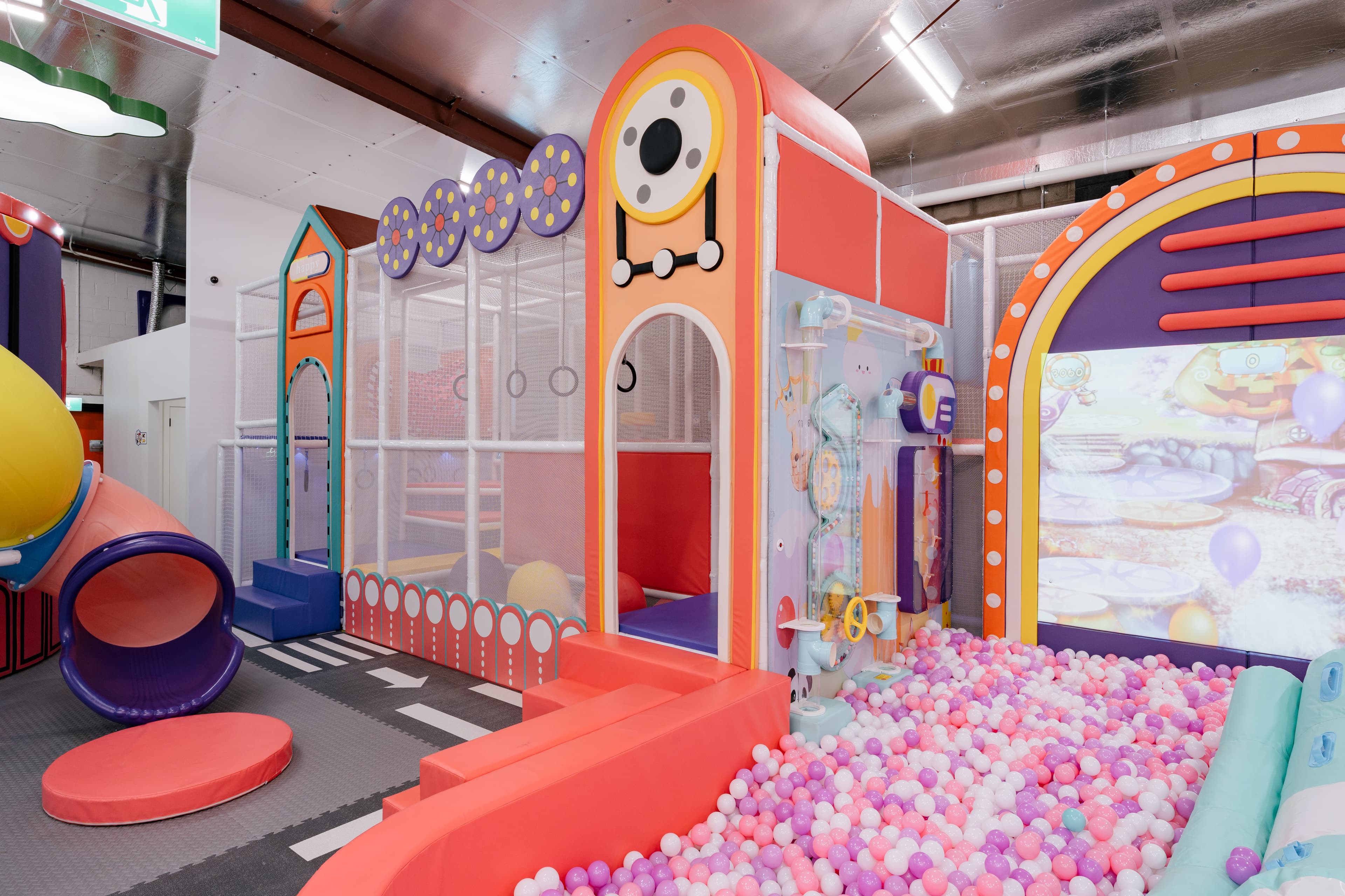 Children climbing and moving through a warm-toned adventure play area inside the venue.